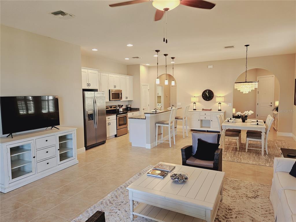 10468 Crooked Creek Drive Venice, FL 34293 - Photo 8 of 44 an open kitchen with stainless steel appliances kitchen island granite countertop a stove and a living room view