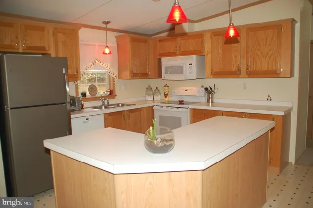 a kitchen with stainless steel appliances granite countertop a dining table chairs a refrigerator and a stove