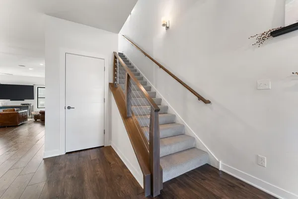 a view of a livingroom with wooden floor and stairs