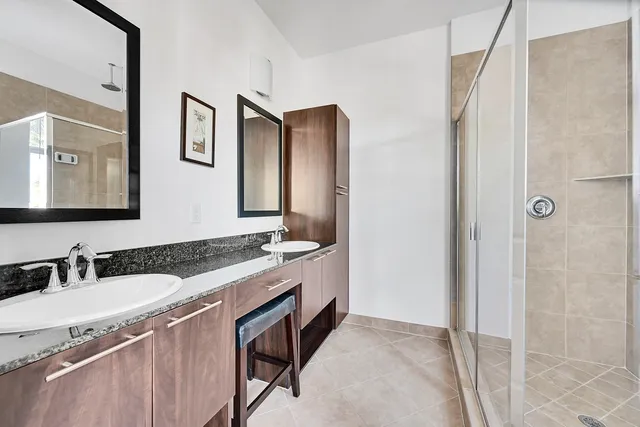 a bathroom with a granite countertop double vanity sink and mirror