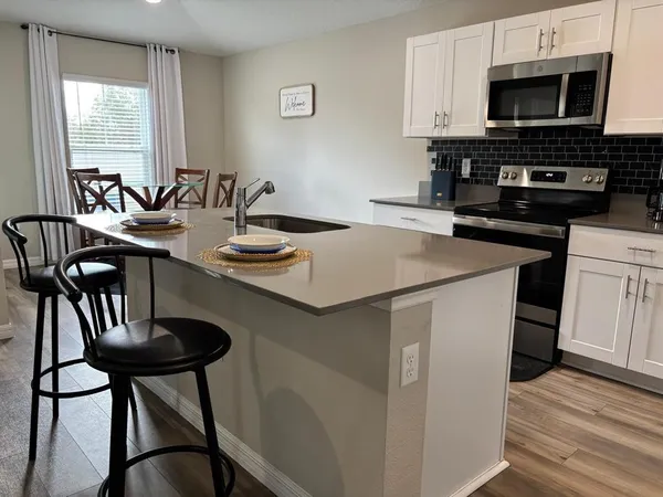 a kitchen with stainless steel appliances kitchen island a table chairs in it and wooden floors