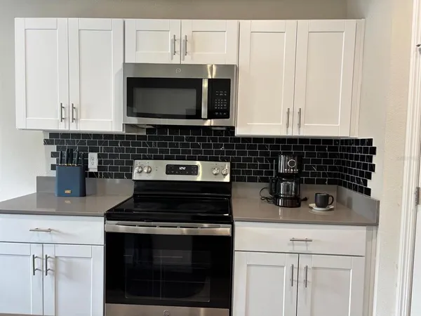 a kitchen with stainless steel appliances a table chairs microwave and refrigerator