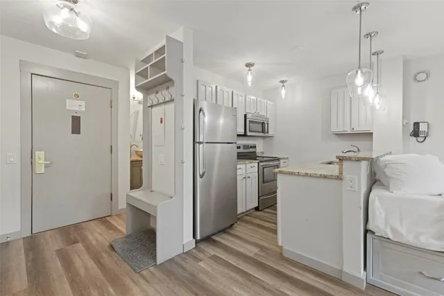 a view of a kitchen with refrigerator and wooden floor