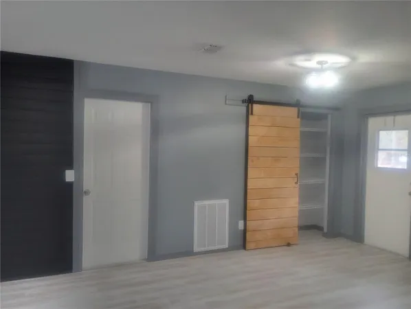 an empty room with wooden floor closet and windows