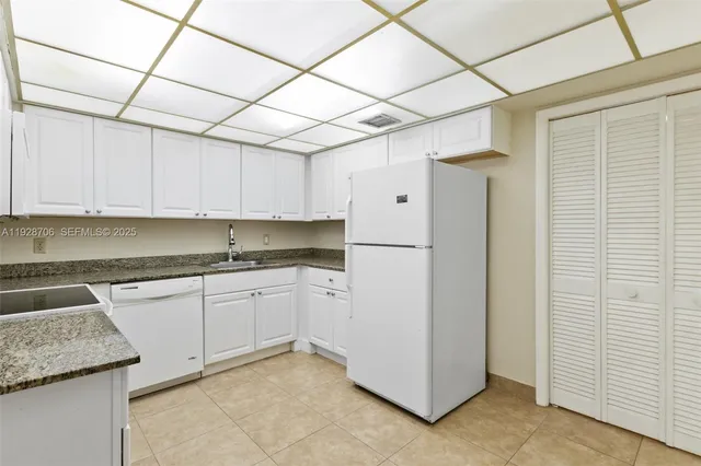 a kitchen with granite countertop white cabinets and white appliances