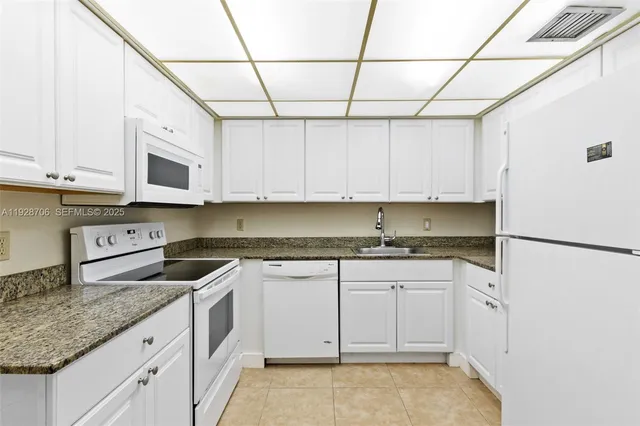 a kitchen with granite countertop white cabinets and white appliances