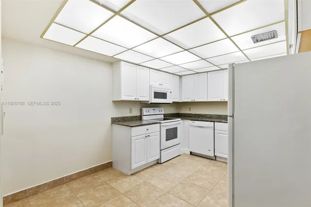 a kitchen with granite countertop white cabinets and white appliances