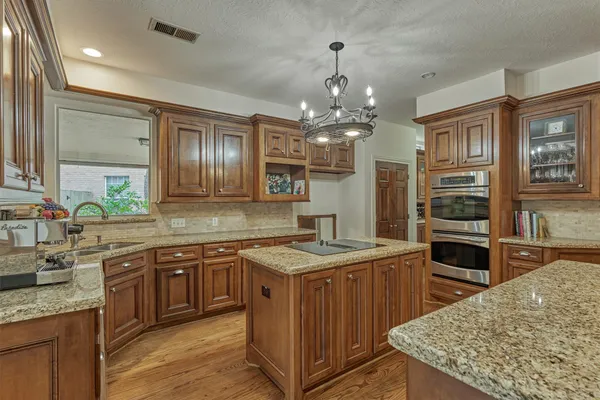 a kitchen with stainless steel appliances granite countertop stove a sink dishwasher and wooden cabinets with wooden floor