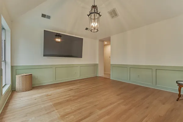a view of an empty room with a window and wooden floor