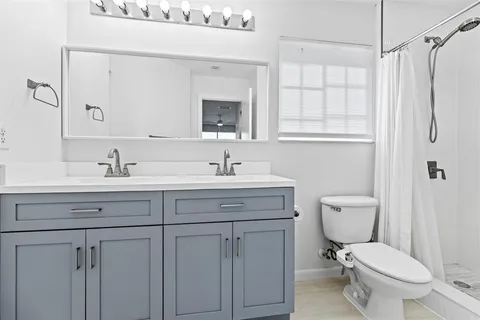 a bathroom with a toilet sink a mirror and shower