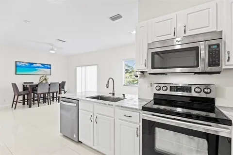 a kitchen with stainless steel appliances a stove a sink a microwave and white cabinets