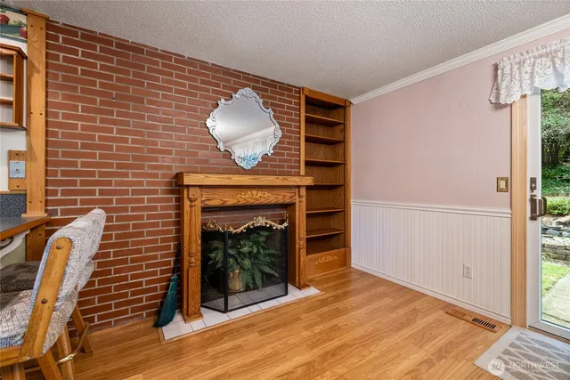 a view of an empty room with wooden floor and a fireplace