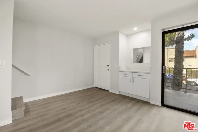 a view of a livingroom with wooden floor and a bathroom