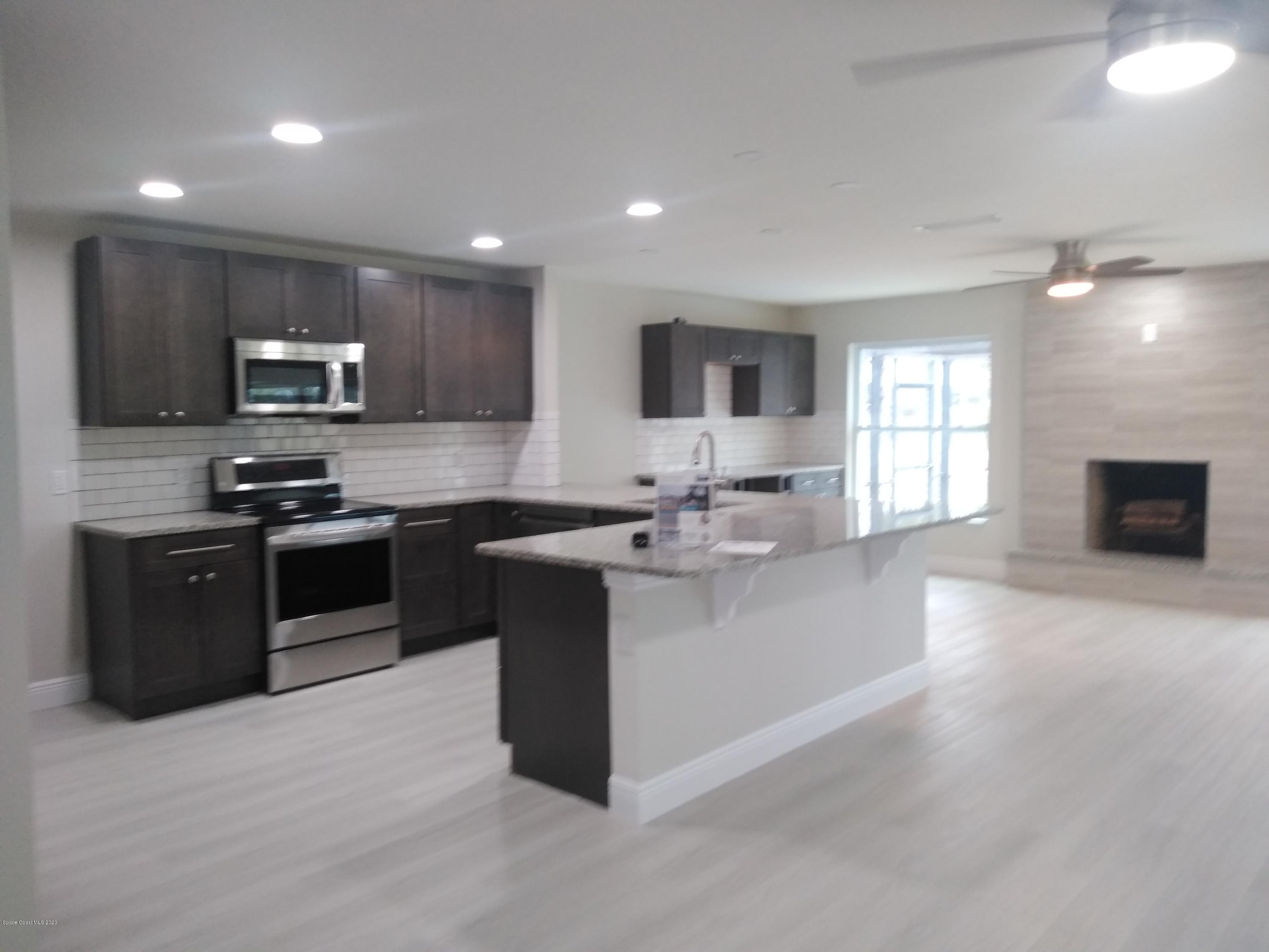 770 Montclair Road Northeast, Unit 1 Palm Bay, FL 32905 - Photo 11 of 23 a kitchen with stainless steel appliances kitchen island granite countertop a stove top oven a sink and a refrigerator