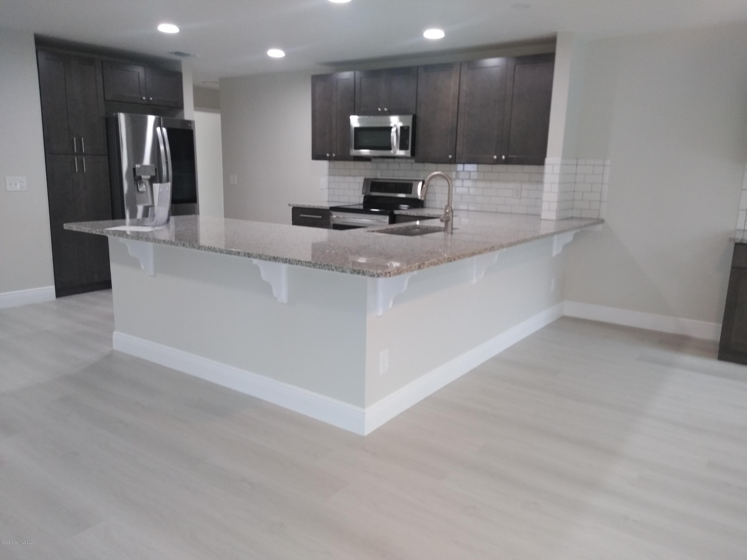 770 Montclair Road Northeast, Unit 1 Palm Bay, FL 32905 - Photo 12 of 23 a large kitchen with stainless steel appliances kitchen island granite countertop a large counter top and a stove top oven