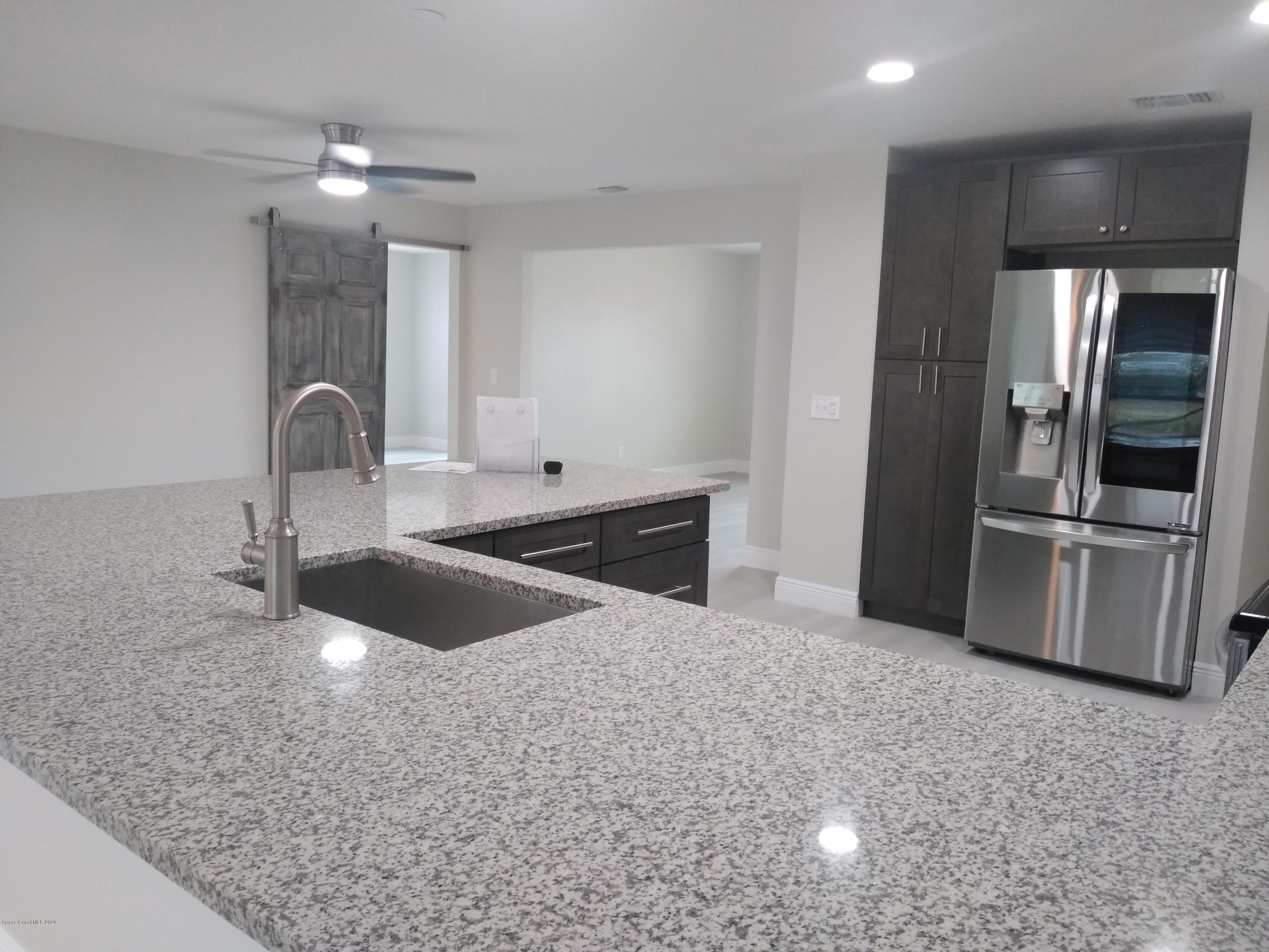 770 Montclair Road Northeast, Unit 1 Palm Bay, FL 32905 - Photo 13 of 23 a kitchen with stainless steel appliances granite countertop a sink and a refrigerator