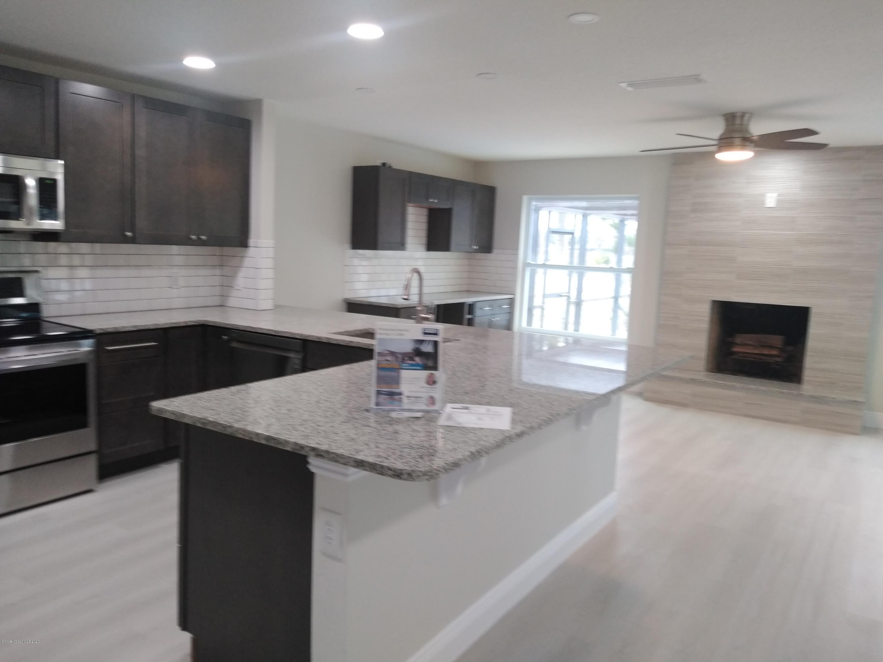 770 Montclair Road Northeast, Unit 1 Palm Bay, FL 32905 - Photo 23 of 23 a kitchen with stainless steel appliances granite countertop a sink dishwasher a stove and a refrigerator with wooden floor