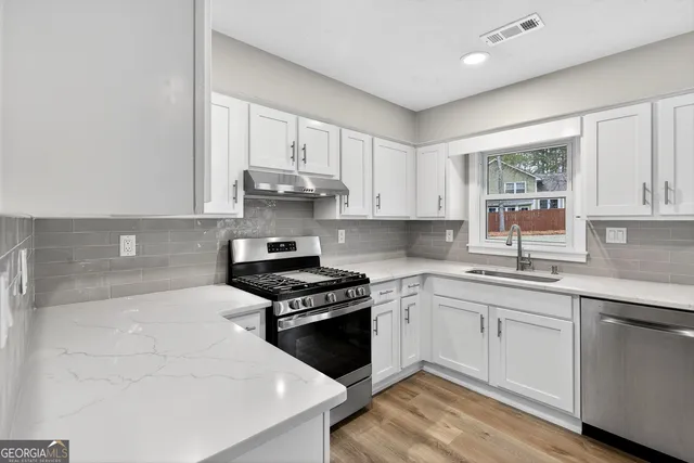 a kitchen with stainless steel appliances granite countertop a stove and white cabinets