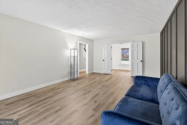 a view of an empty room with a window and wooden floor