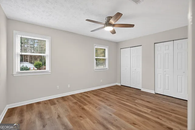 an empty room with wooden floor and ceiling fan