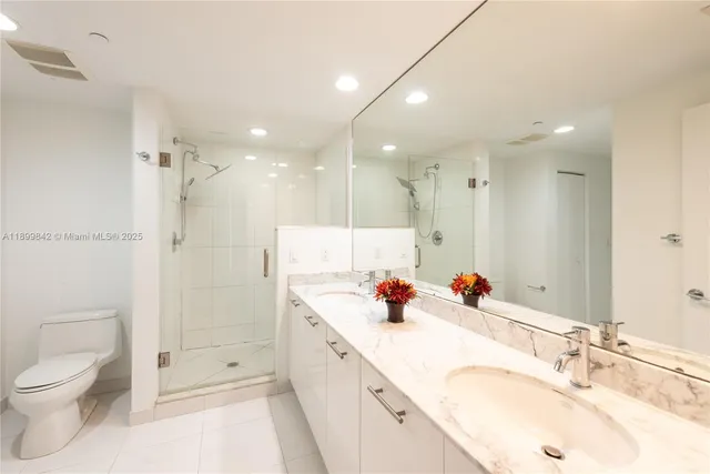 a bathroom with a double vanity sink mirror double shower and a toilet