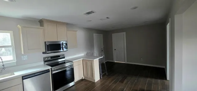 a kitchen with wooden floor and black appliances