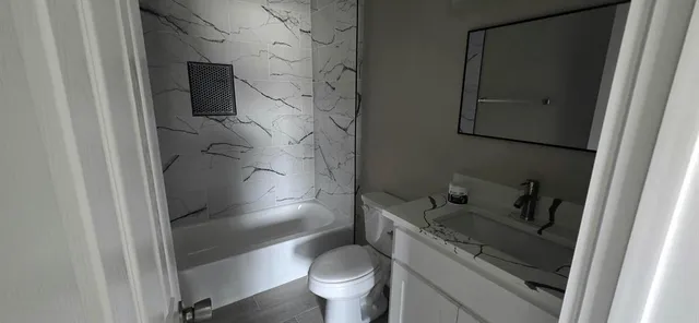 a bathroom with a granite countertop sink toilet and shower