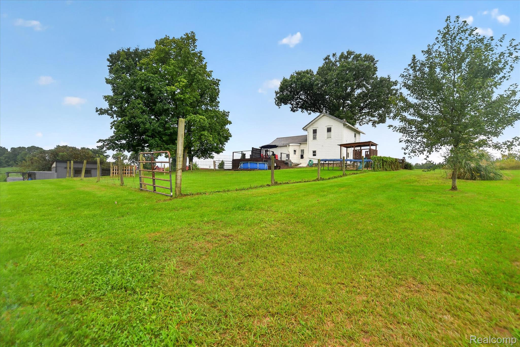 9413 Rives Junction Road Rives Junction, MI 49277 - Photo 36 of 43 Expansive green lawn with mature trees, fenced perimeter, and a detached white residence with an attached covered porch