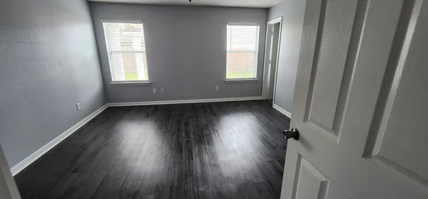 an empty room with wooden floor and windows