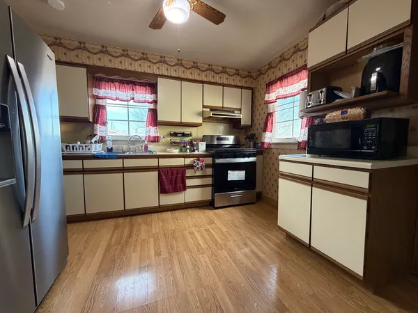 a kitchen with stainless steel appliances granite countertop a refrigerator a stove top oven a sink dishwasher and wooden cabinets with wooden floor