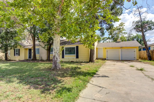 a view of a house with a yard and large tree