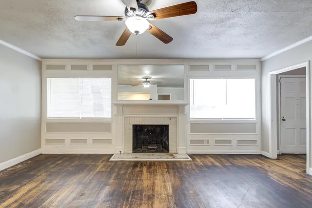 a view of an empty room with window and wooden floor