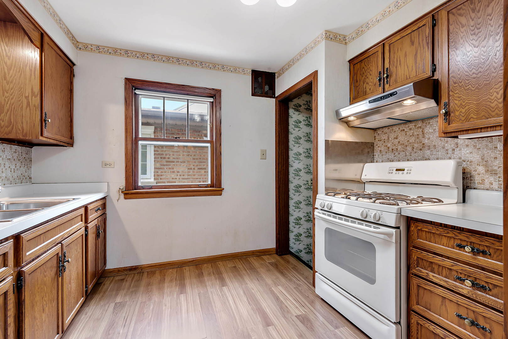 7438 Kenneth Avenue Skokie, IL 60076 - Photo 6 of 17 a kitchen with a stove wooden floor and a sink