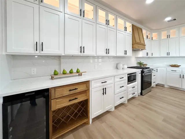 a kitchen with stainless steel appliances granite countertop a stove a sink dishwasher and white cabinets with wooden floor