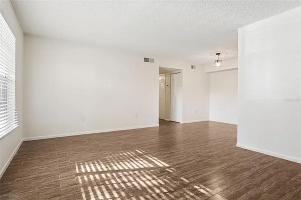 a view of an empty room with wooden floor and a window