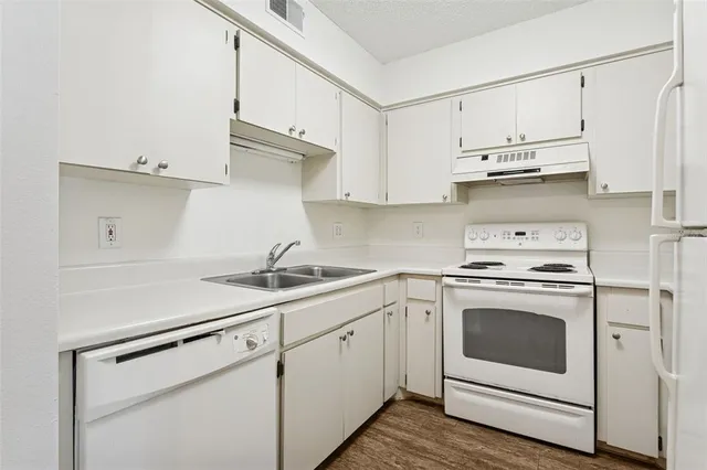 a kitchen with white cabinets sink and white stainless steel appliances