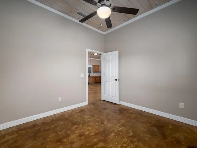 an empty room with a ceiling fan and carpet