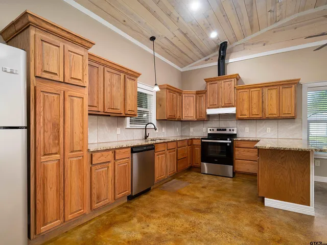 a kitchen with stainless steel appliances granite countertop a refrigerator a stove top oven a sink and dishwasher