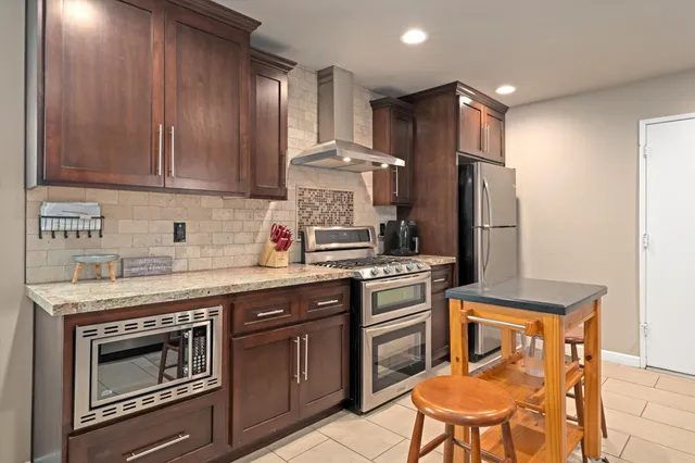 a kitchen with stainless steel appliances granite countertop a stove a sink dishwasher and a refrigerator