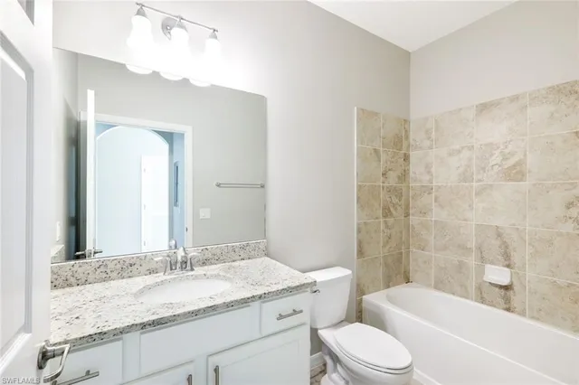 a bathroom with a granite countertop sink toilet mirror and bathtub