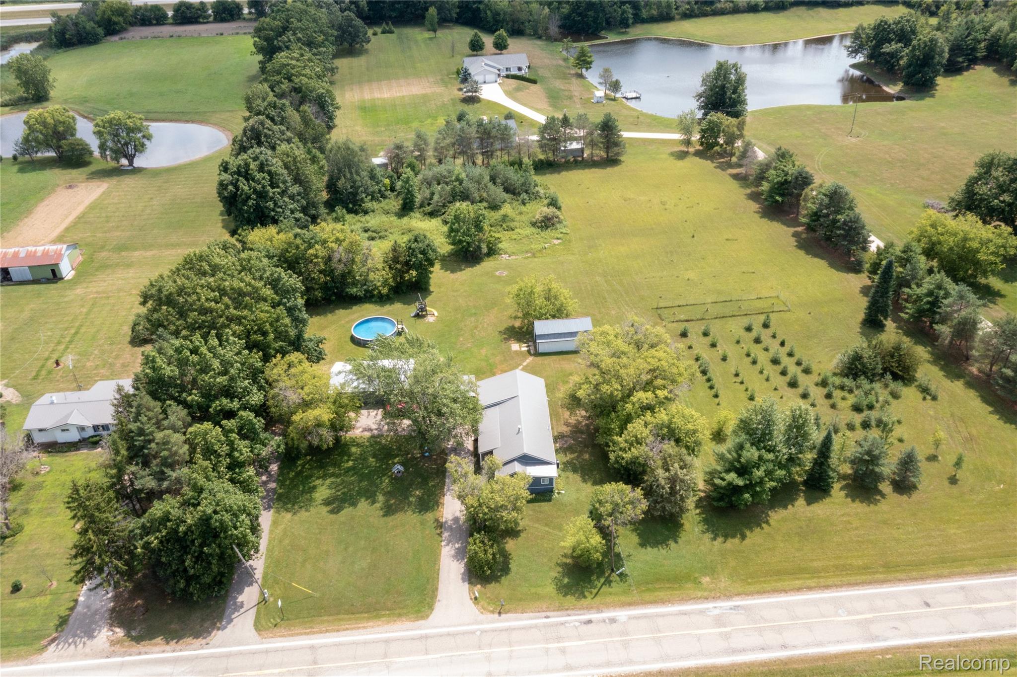 5761 Genesee Road Lapeer, MI 48446 - Photo 32 of 52 Expansive acreage featuring a main residence, multiple outbuildings, mature trees, open fields, and a private pond