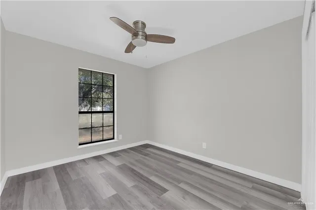 an empty room with wooden floor chandelier and windows
