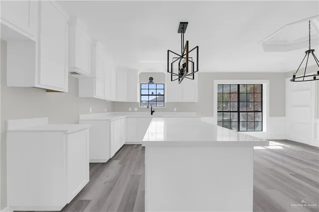 a open kitchen with white cabinets and wooden floor