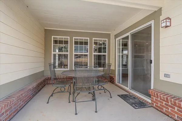 a balcony with table and chairs and wooden fence