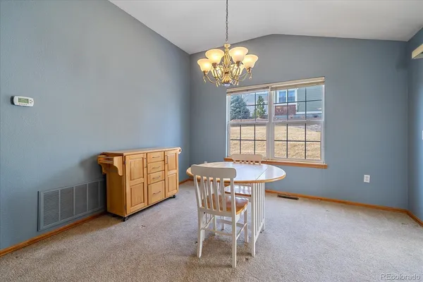 a view of a dining room with furniture a chandelier and window