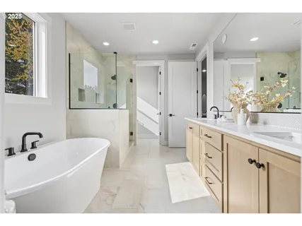 a bathroom with a tub a sink double vanity and a mirror