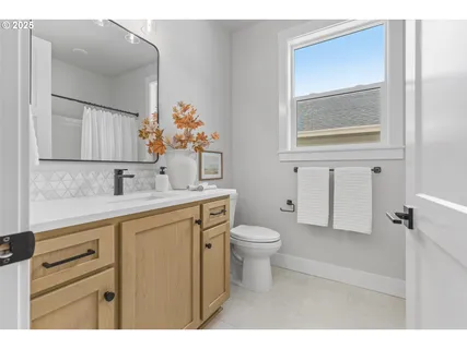 a bathroom with a toilet a sink a mirror and a window