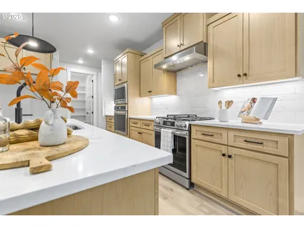 a kitchen with stainless steel appliances granite countertop a sink a stove and white cabinets