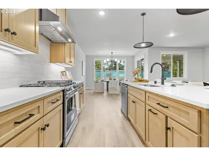 a kitchen with stainless steel appliances granite countertop a sink a stove and a wooden floors