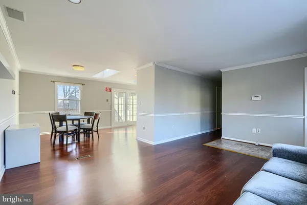 a kitchen with granite countertop a stove a sink dishwasher a dining table and chairs with wooden floor